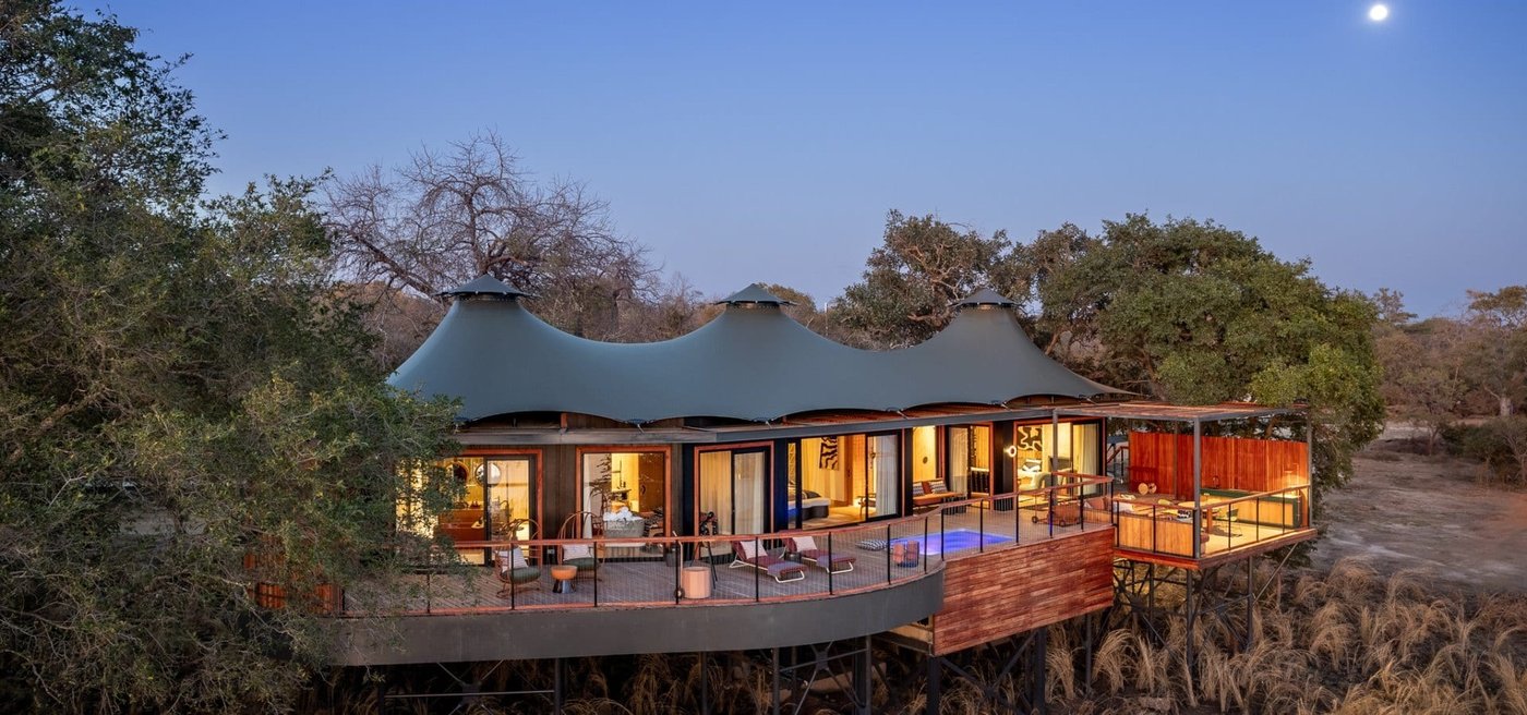 Anantara Tented Camp Kafue River's canvas roofs rise above the bush at dusk.