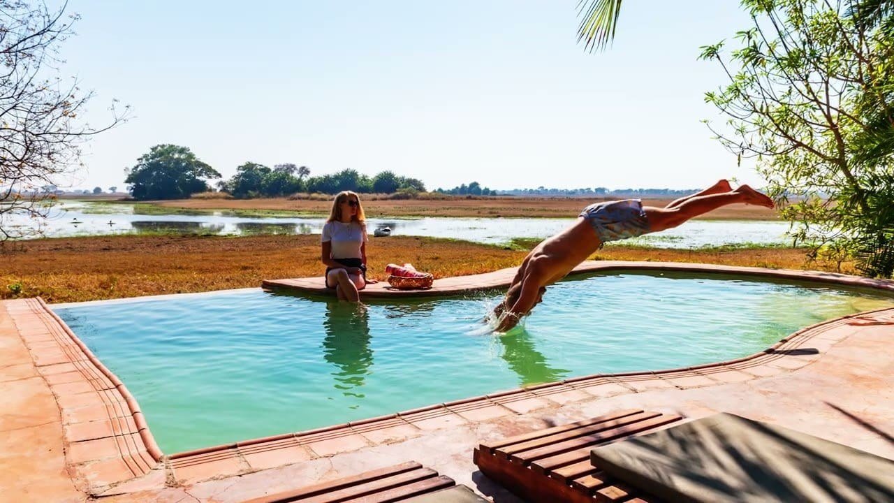 A guest dives into the infinity pool overlooking the floodplain at Busanga Plains Camp.