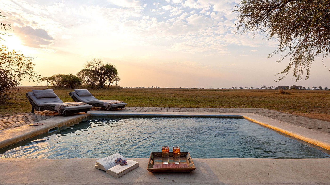 An infinity pool overlooks the plains at sunset at Chisa Busanga Camp.
