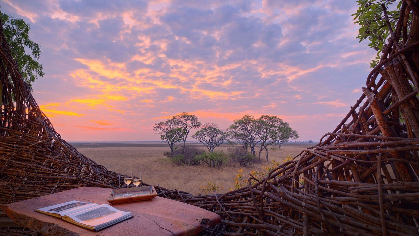 Woven nest walls frame a sunset view over the plains at Chisa Busanga Camp.