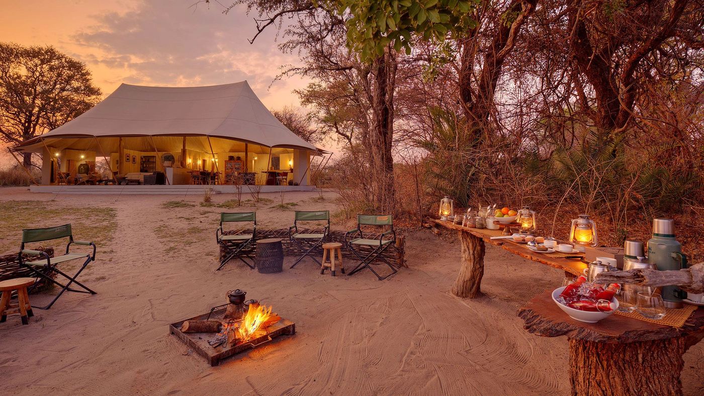 A long table is set for dinner beside the fire pit at Chisa Busanga Camp.