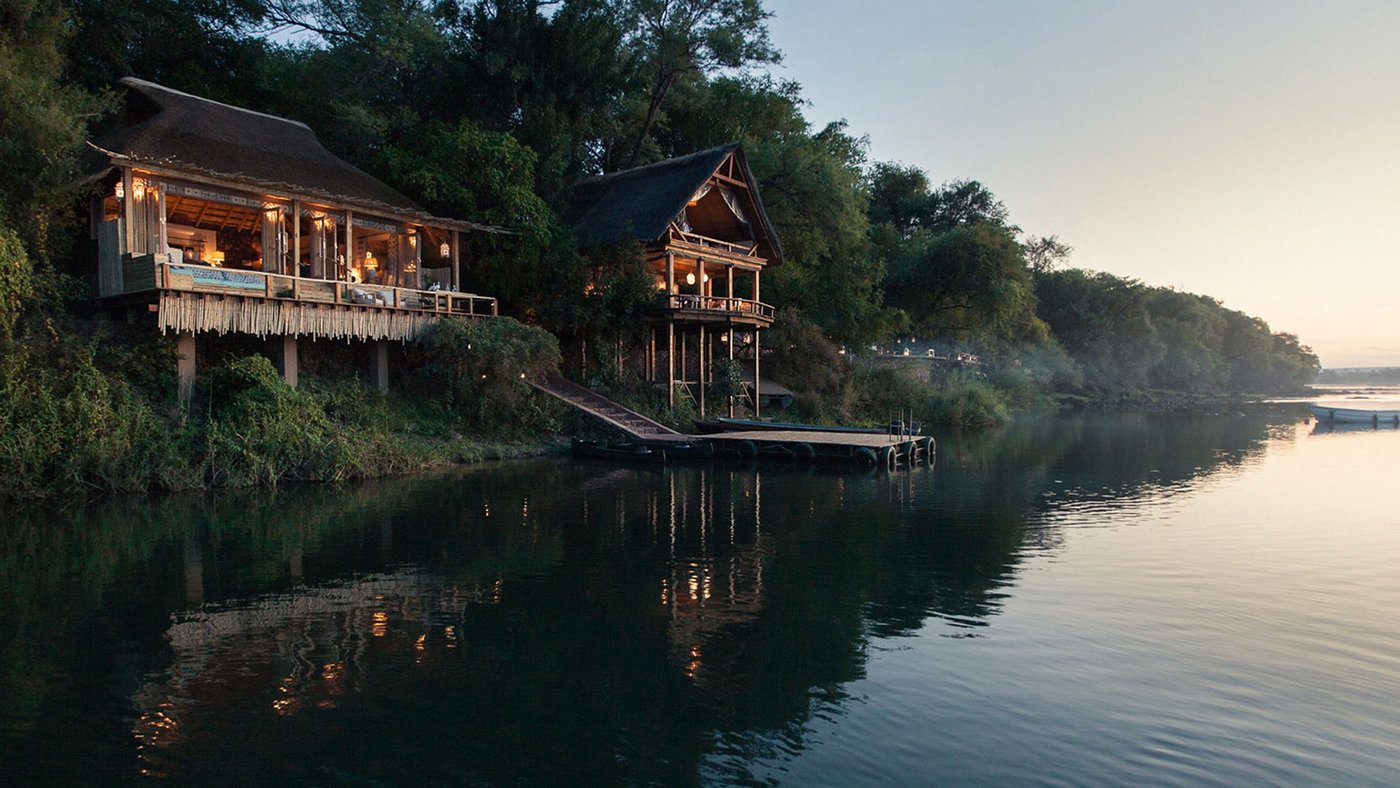 The main lounge building sits on the riverbank at dusk at Chisa Busanga Camp.