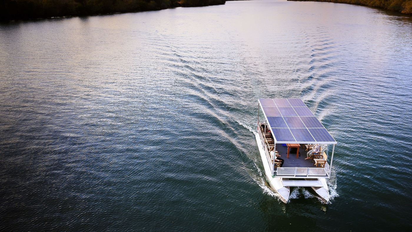 A solar-powered boat glides across calm water near Ila Safari Lodge.