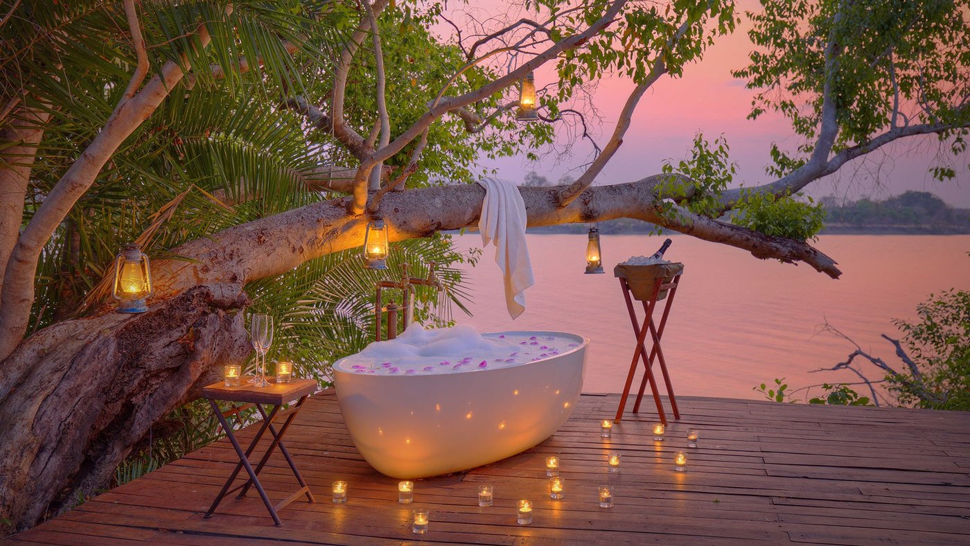 A freestanding bathtub sits on a deck beneath a tree at Ila Safari Lodge.