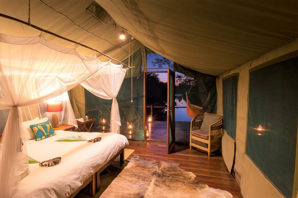 A mosquito-net canopy bed faces the open deck at KaingU Safari Lodge.