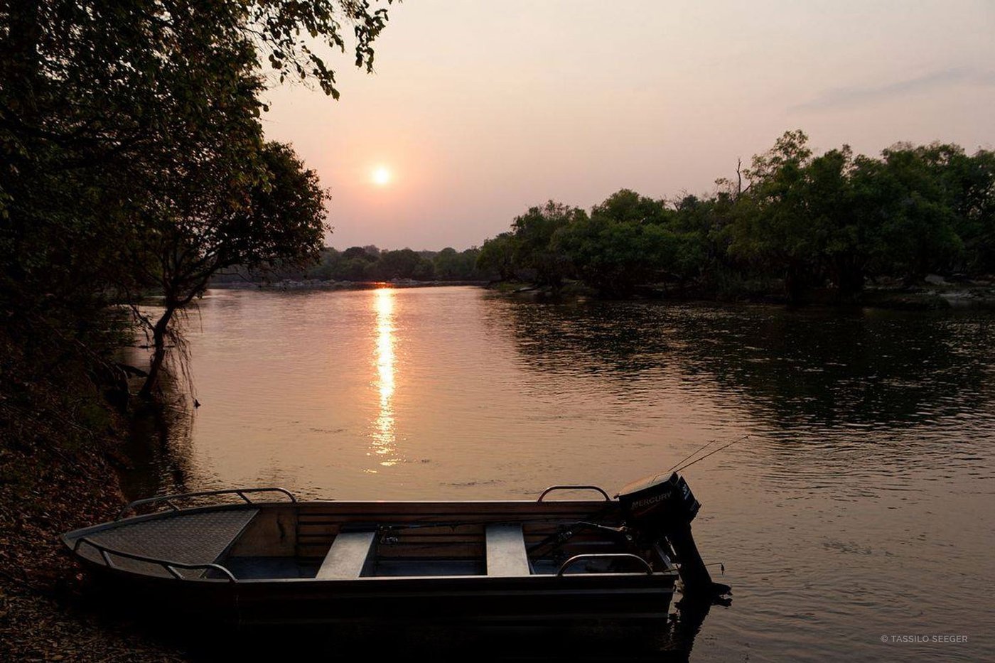 A small boat drifts on the river at sunset near Lunga Kikuji Camp.