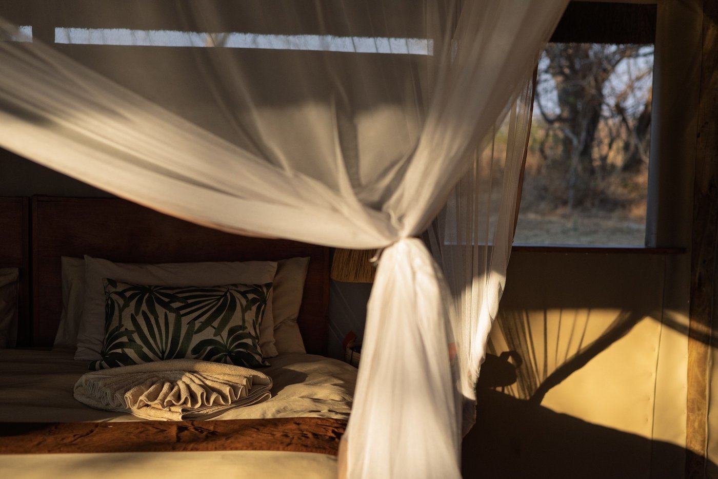 A tented bedroom features a gauzy mosquito net at Lwenge River Camp.