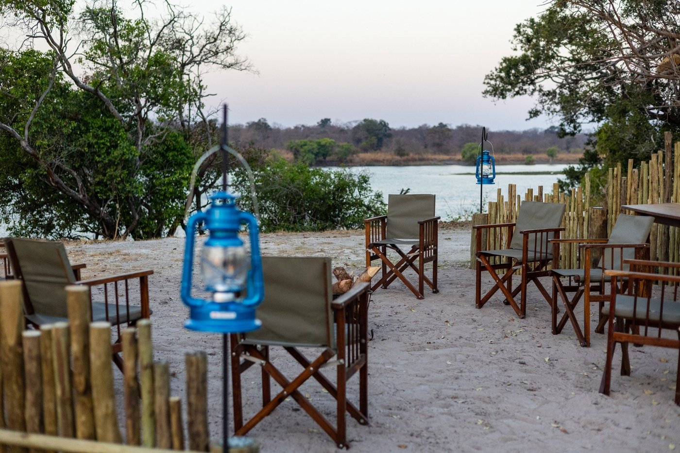 Lantern-lit chairs line the riverside deck at dusk at Lwenge River Camp.