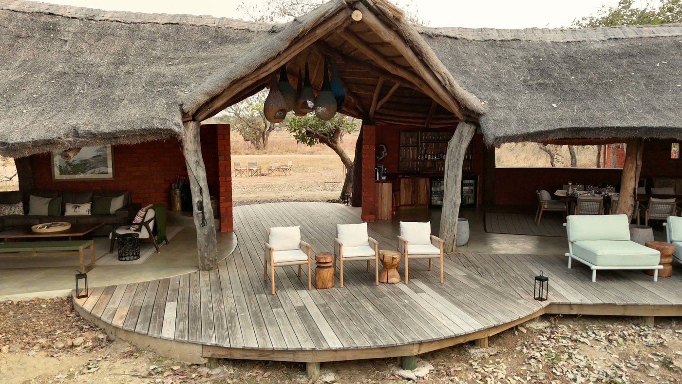 White cushioned seating fills the open-air lounge at Mawimbi Bush Camp.