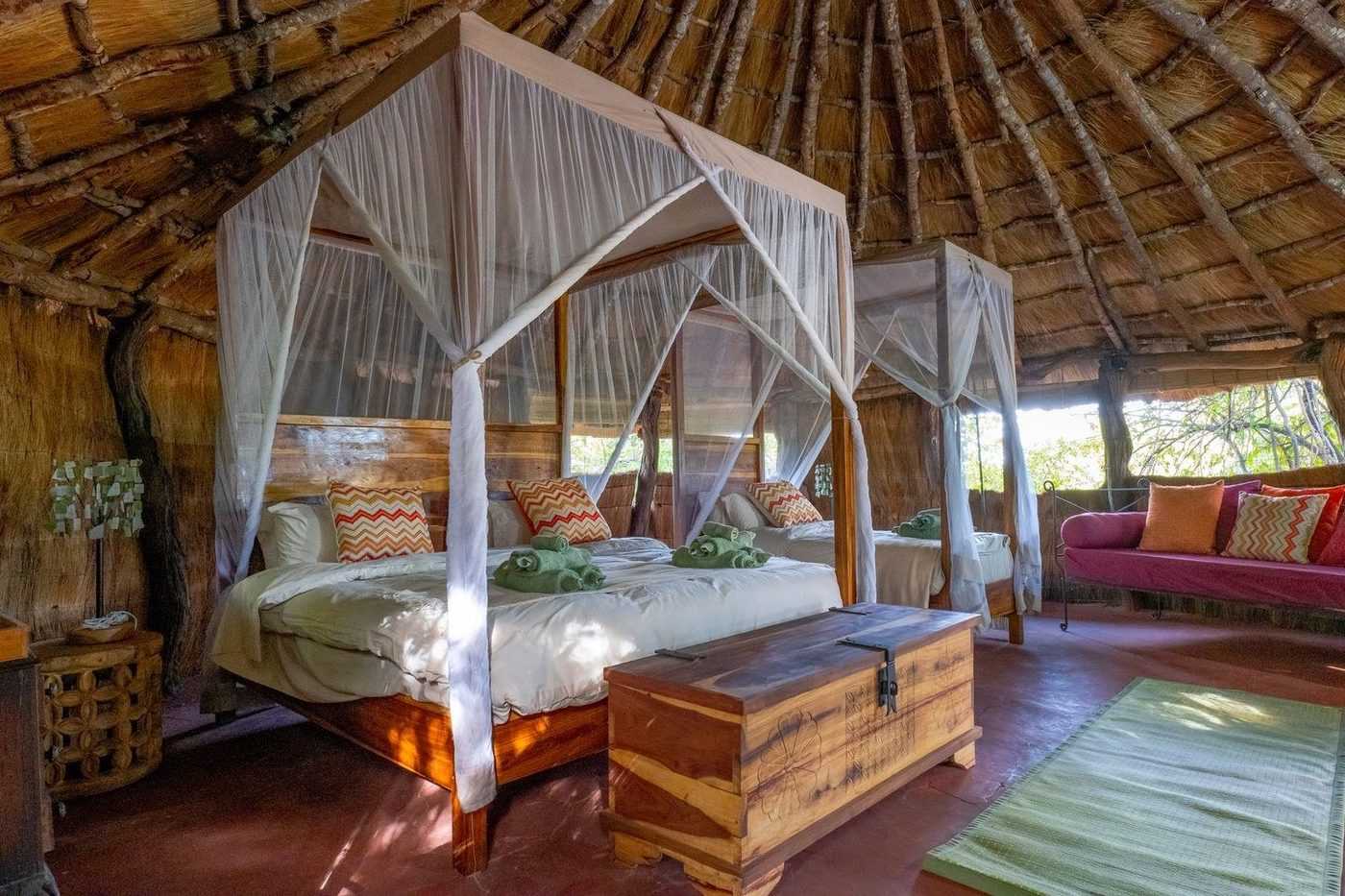 A four-poster bed sits beneath a thatched roof at McBrides' Camp.