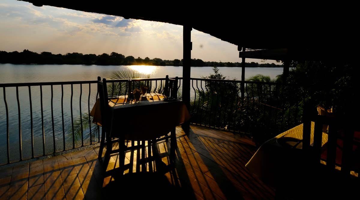 Sunset lights the river beyond a dining deck at Mukambi Safari Lodge.