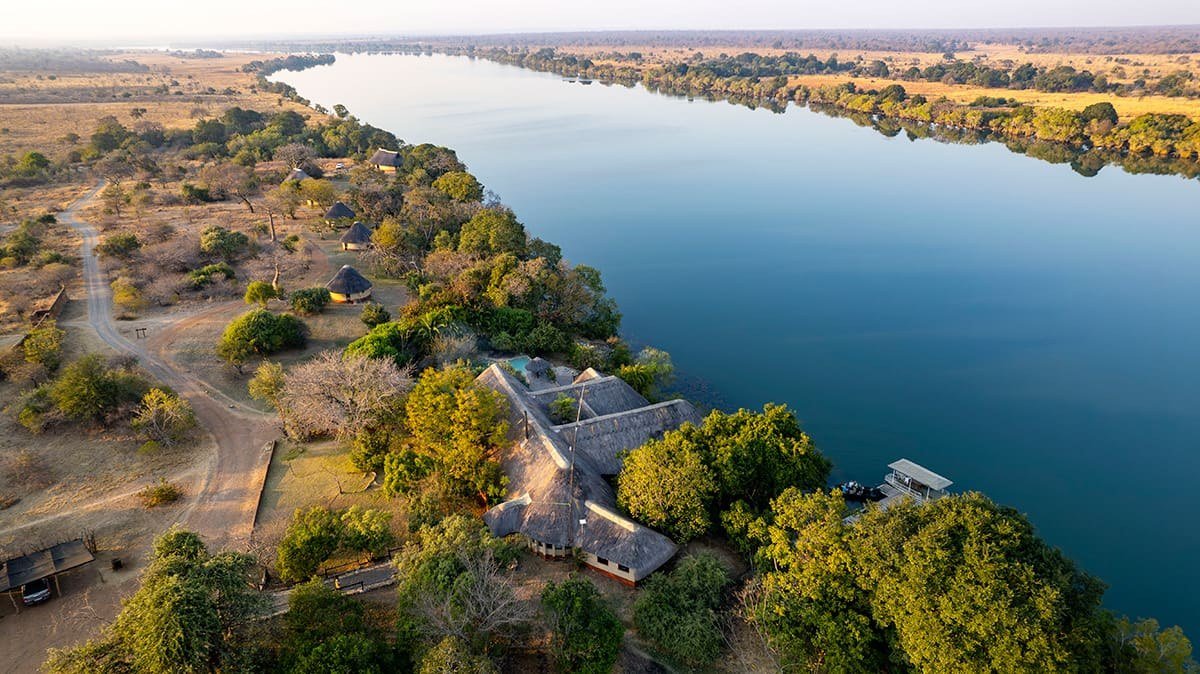 Thatched roofs of Mukambi Safari Lodge line the bank of the Kafue River.