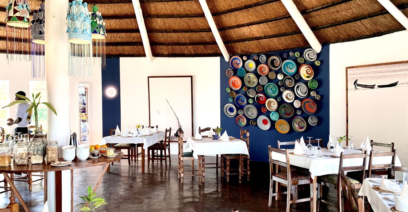 A dining room is set with white tablecloths at Musungwa Safari Lodge.