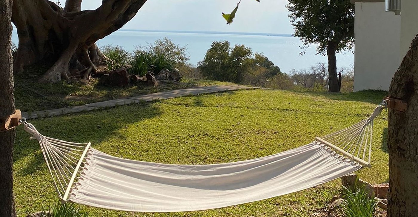 A hammock hangs beneath a tree overlooking the lake at Musungwa Safari Lodge.