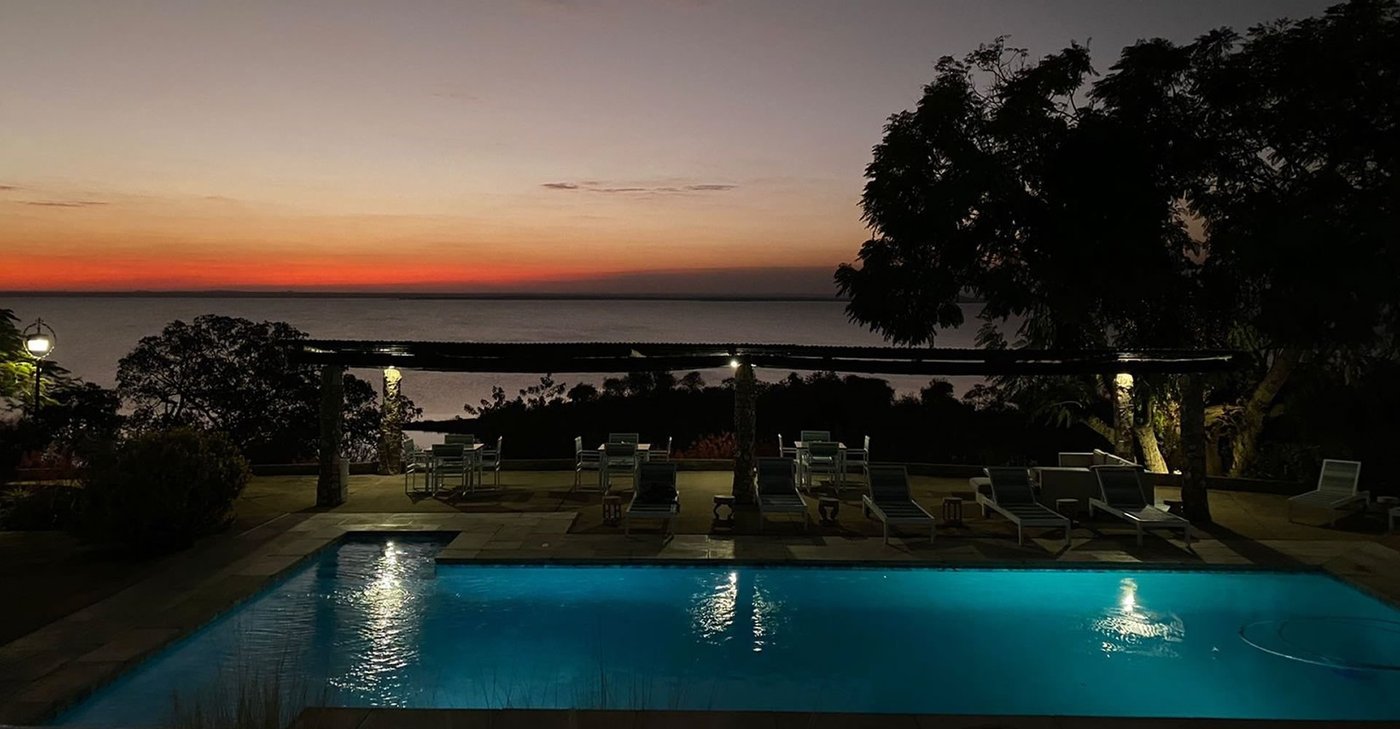 The pool glows at dusk under a pergola at Musungwa Safari Lodge.