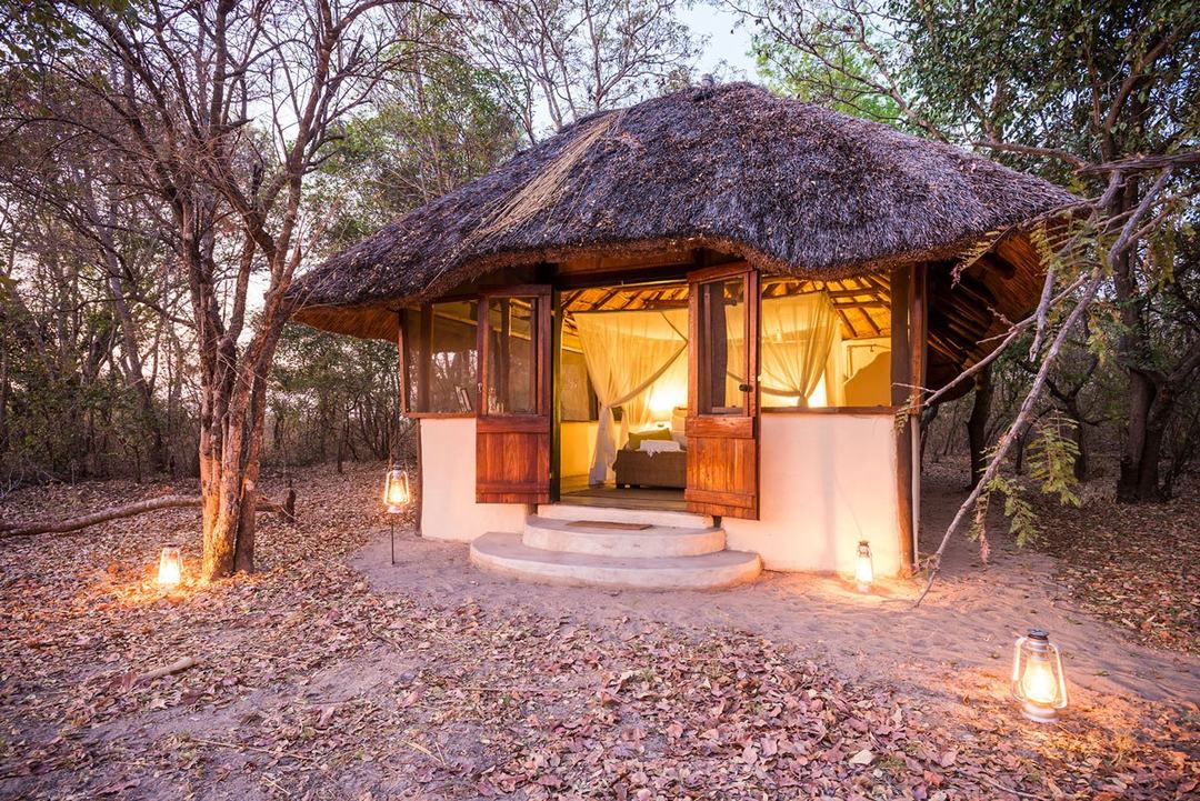 Lantern light glows at a thatched chalet at dusk at Nanzhila Plains Camp in Kafue.