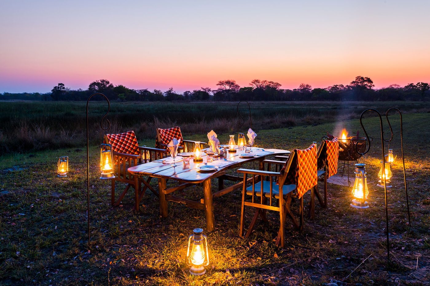A dinner table is lit by lanterns on the plains at Nanzhila Plains Camp.