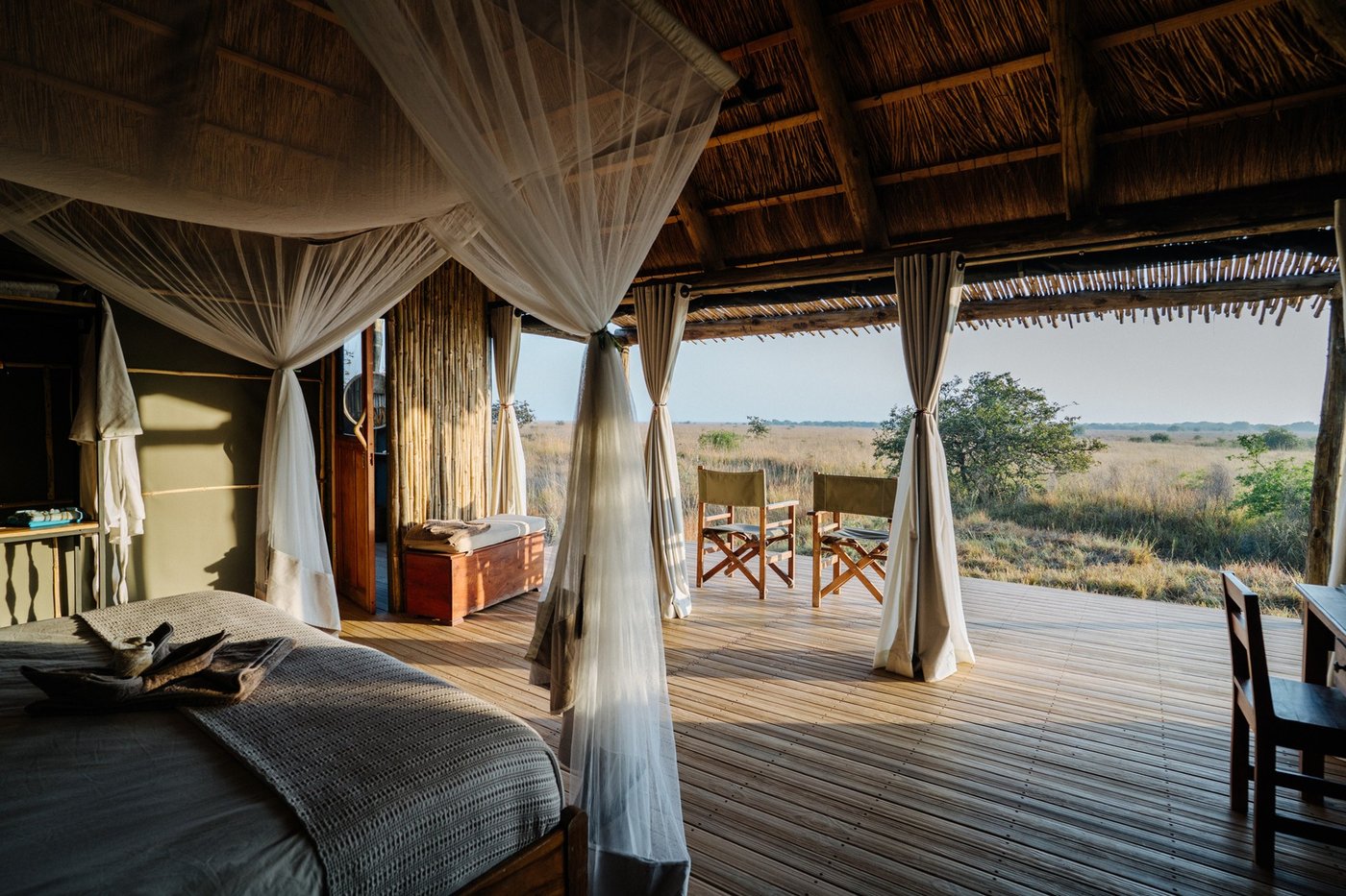 Sheer curtains frame a bed with a plains view at Ntemwa-Busanga Camp.