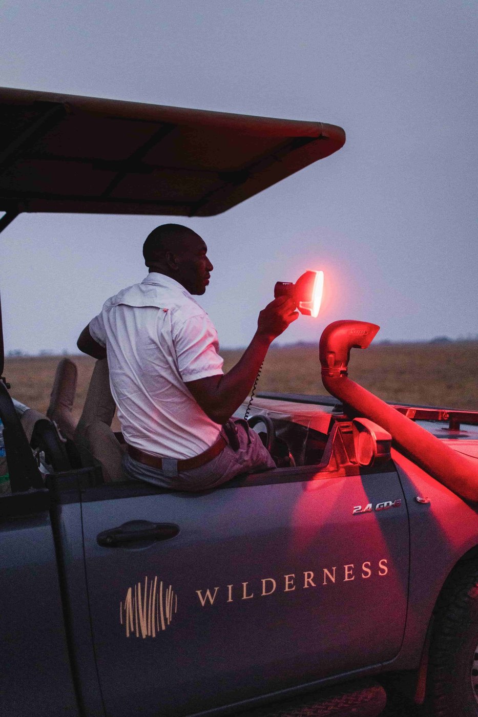 A guide shines a spotlight from the vehicle on a night drive at Shumba Camp.